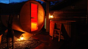 Una cabaña de madera con interior circular, una puerta roja y revestimiento de madera.
