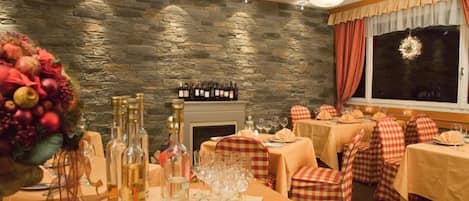 Un restaurante con paredes de piedra, mesas dispuestas con copas de vino y sillas a cuadros.