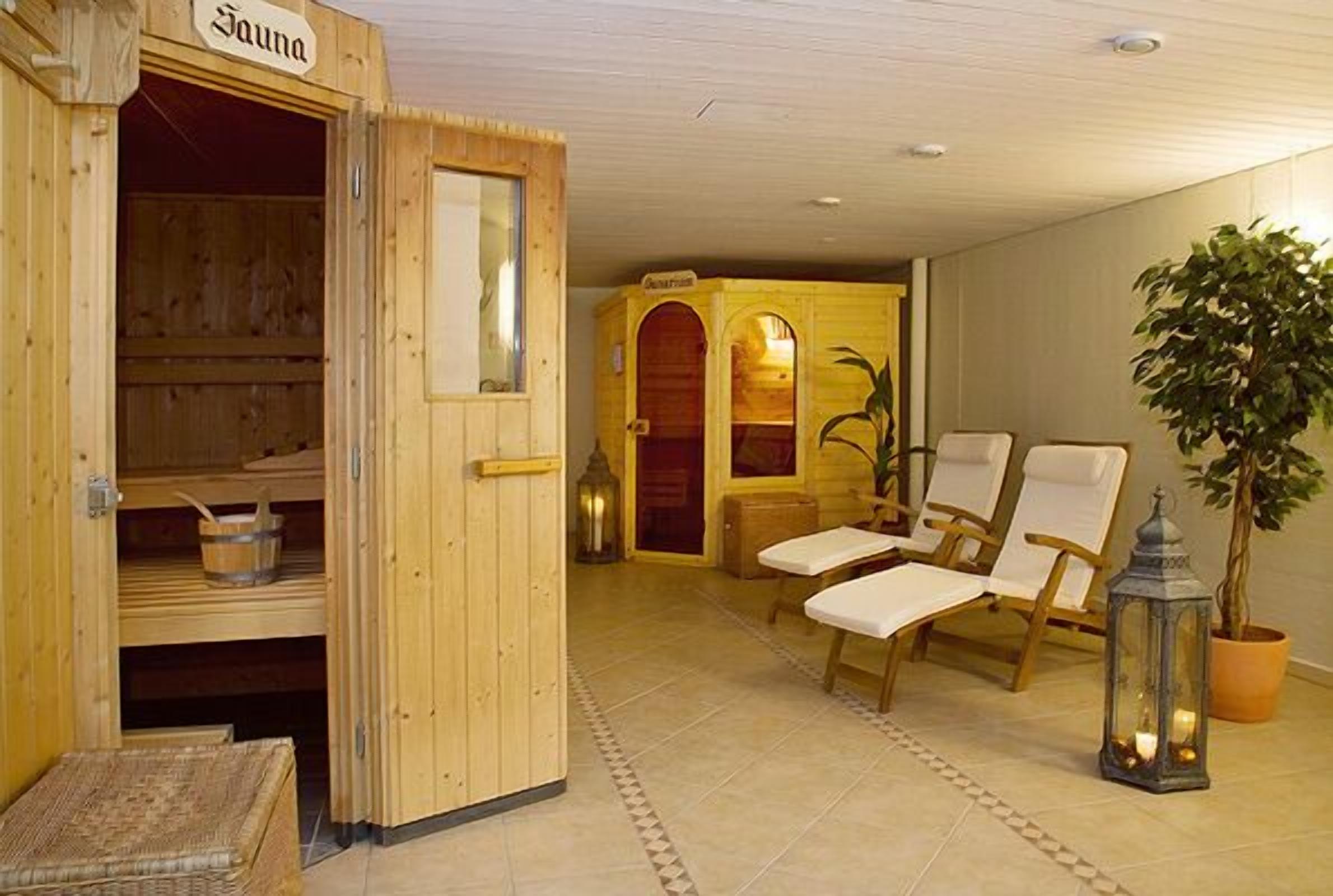 Un cuarto de sauna con bancos de madera, un banco con una toalla, una planta en maceta y un farol.