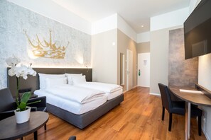 A modern hotel room with a large bed, a desk, and a seating area. - Altstadt Hotel Krone Luzern (Lucerne)