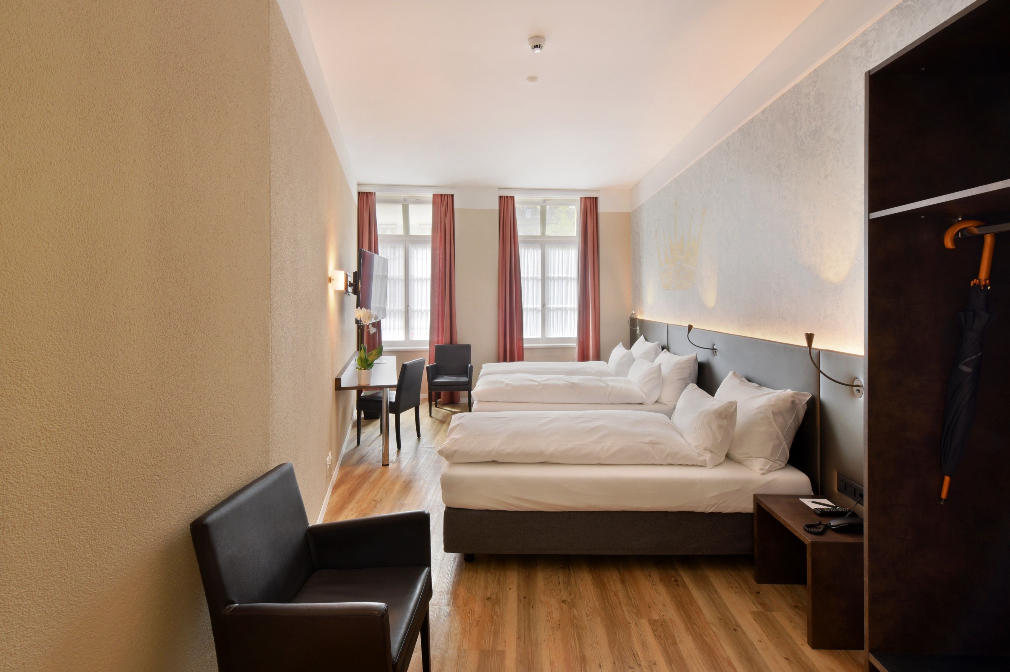 Ein Hotelzimmer mit zwei Betten, einem Schreibtisch und einem Stuhl.