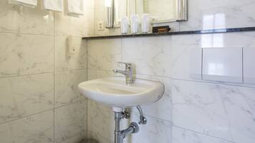A modern bathroom with a marble sink, a toilet, and a mirror.