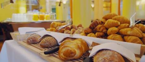 A buffet table with various baked goods including croissants and bread.