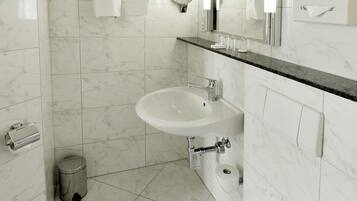 Un baño moderno con un lavabo blanco, inodoro y un espejo sobre el lavabo.