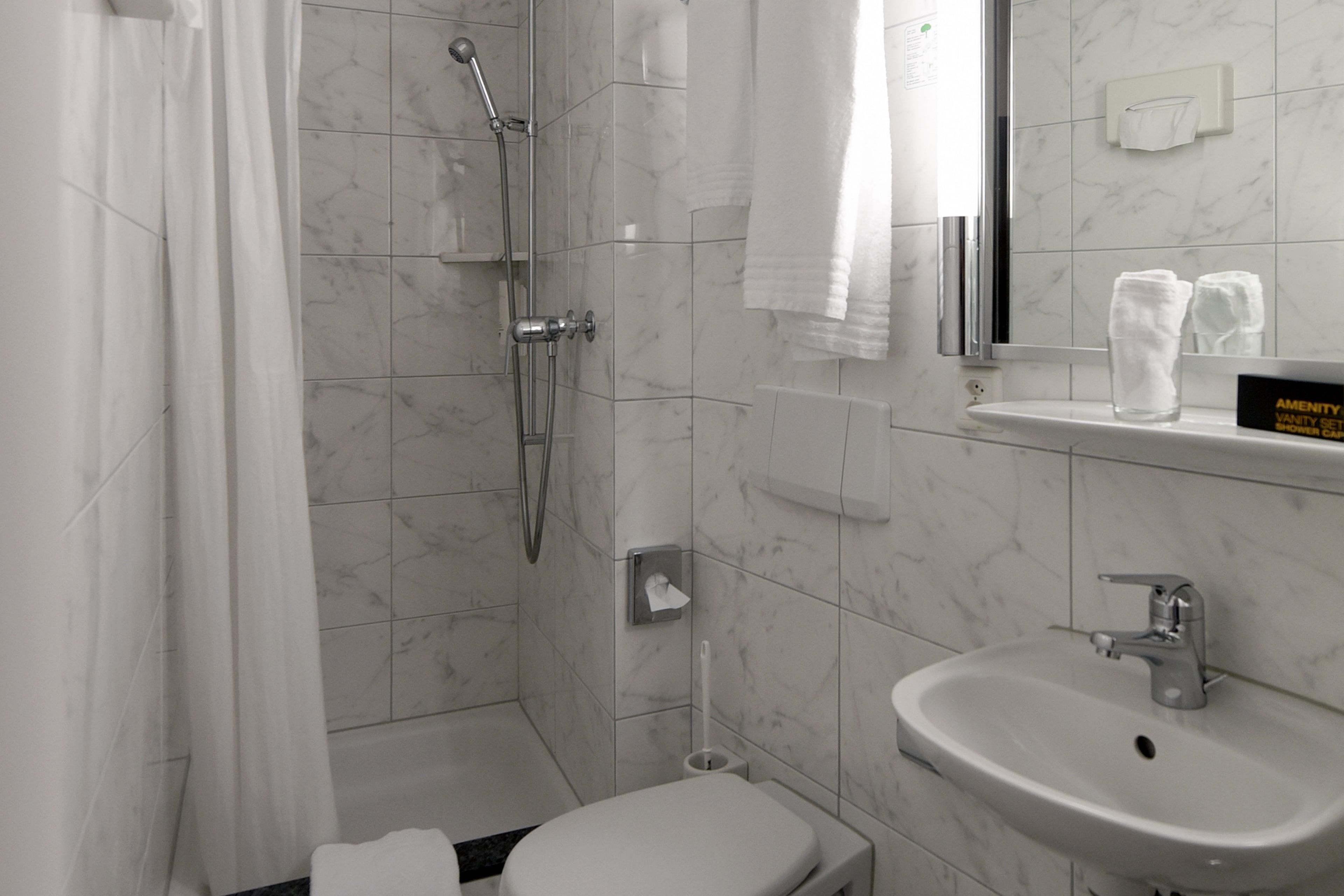 A modern bathroom with a shower, toilet, sink, and a towel rack.