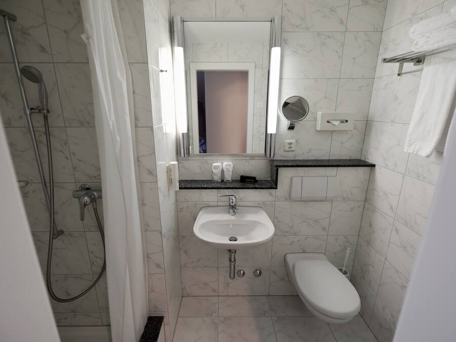 Un baño con ducha, lavabo, inodoro y espejo.
