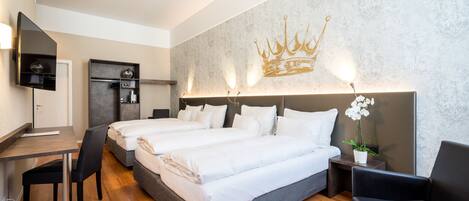A hotel room with two beds, a desk, a chair, a TV, and a decorative wall with a crown design.