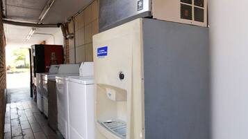 A laundry room with a white dryer, a washing machine, and a water dispenser.