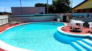 Ein Swimmingpool mit roter Liegefläche und weißen Liegestühlen.