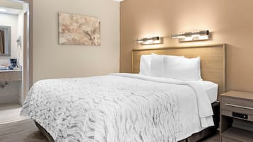 A hotel room with a large bed, a headboard with integrated lighting, a bedside table, and a wall-mounted artwork.
