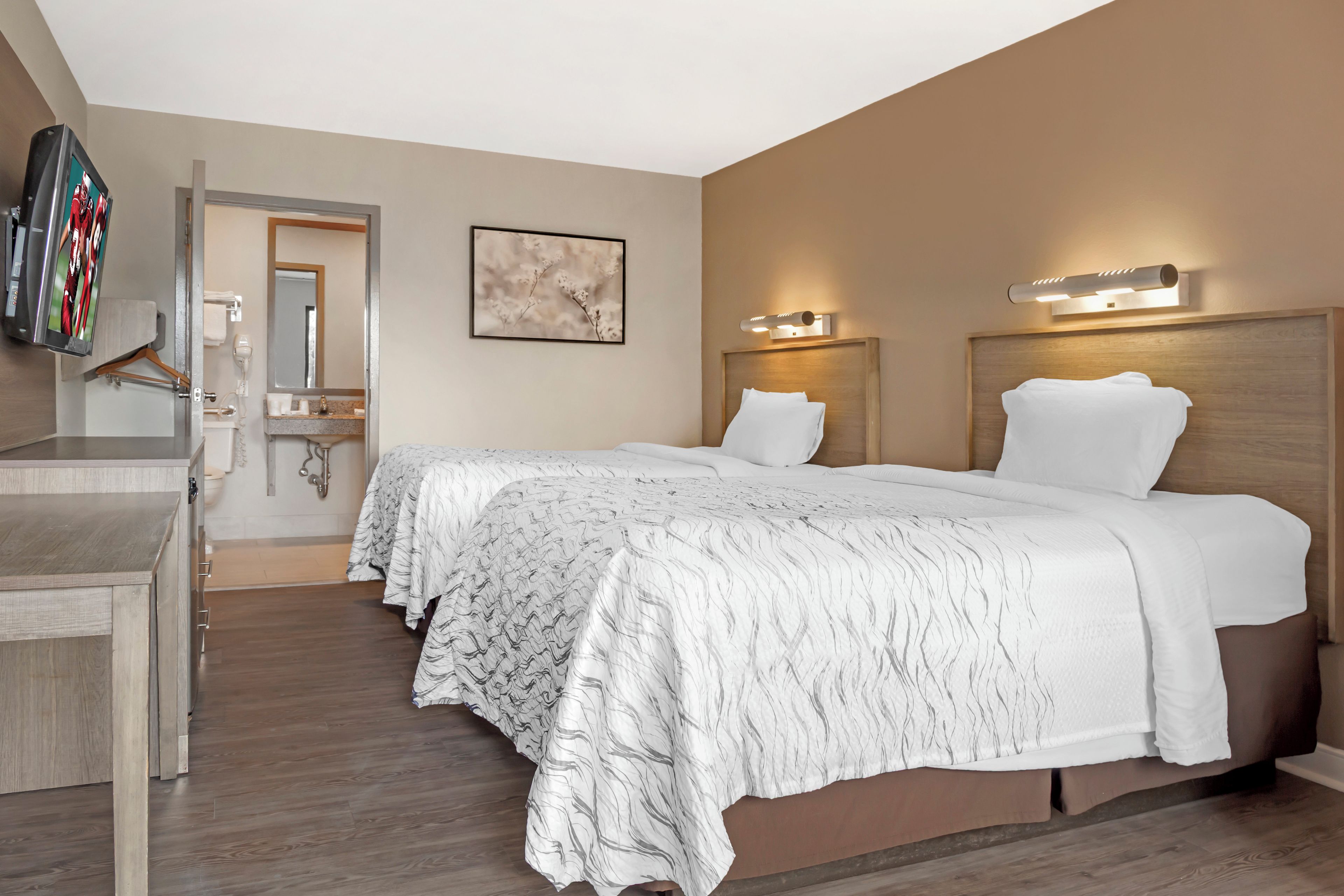 A hotel room with a bed, bedside tables, a mirror, and a wall-mounted TV.