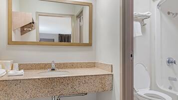 A bathroom with a granite countertop, a sink, a mirror, a towel rack, and a toilet.