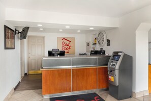 A reception desk with a wooden counter, a clock, and an ATM machine. - Red Roof Inn Bowling Green (Bowling Green)