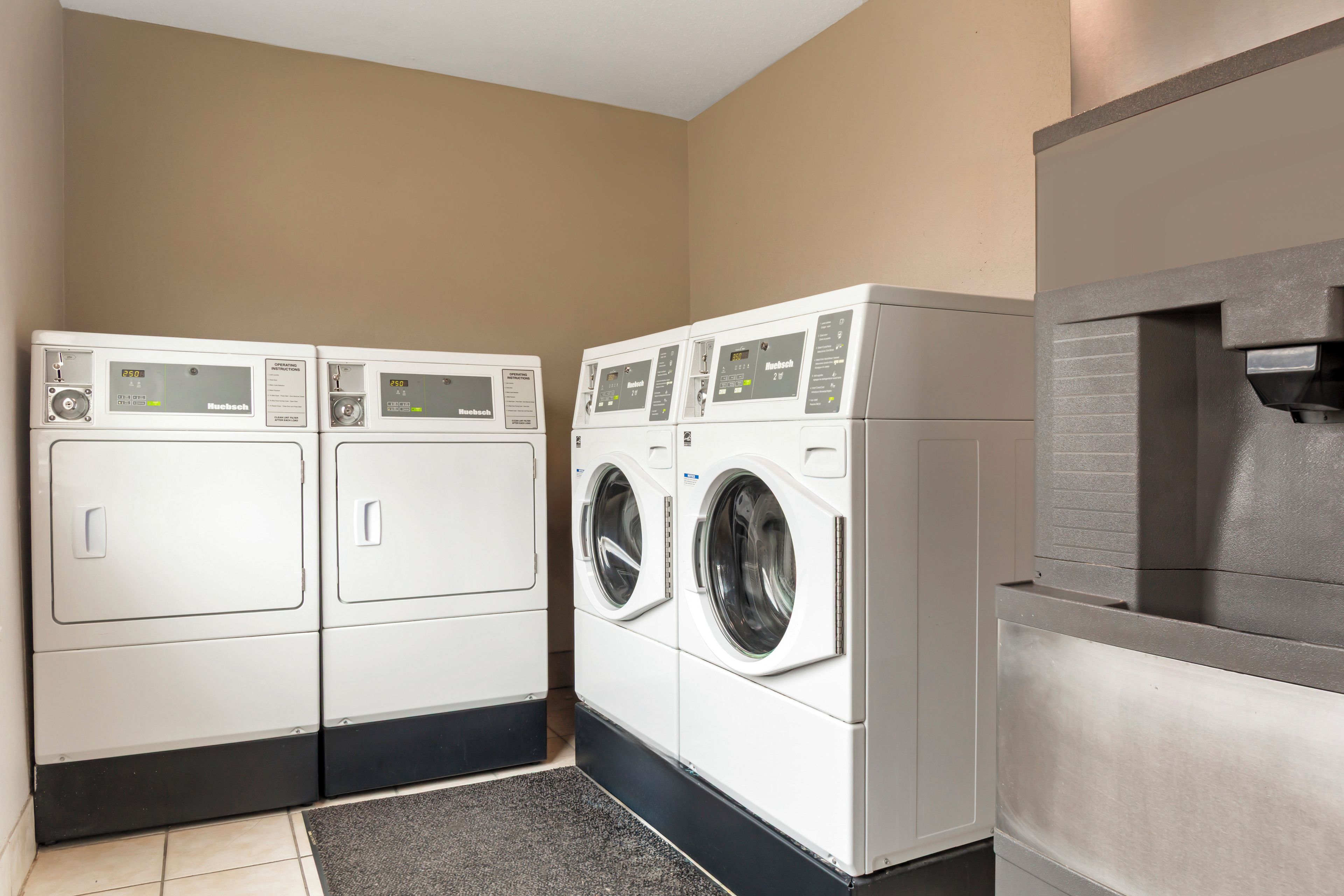 Une buanderie équipée de deux machines à laver à chargement frontal et d’un sèche-linge encastré.