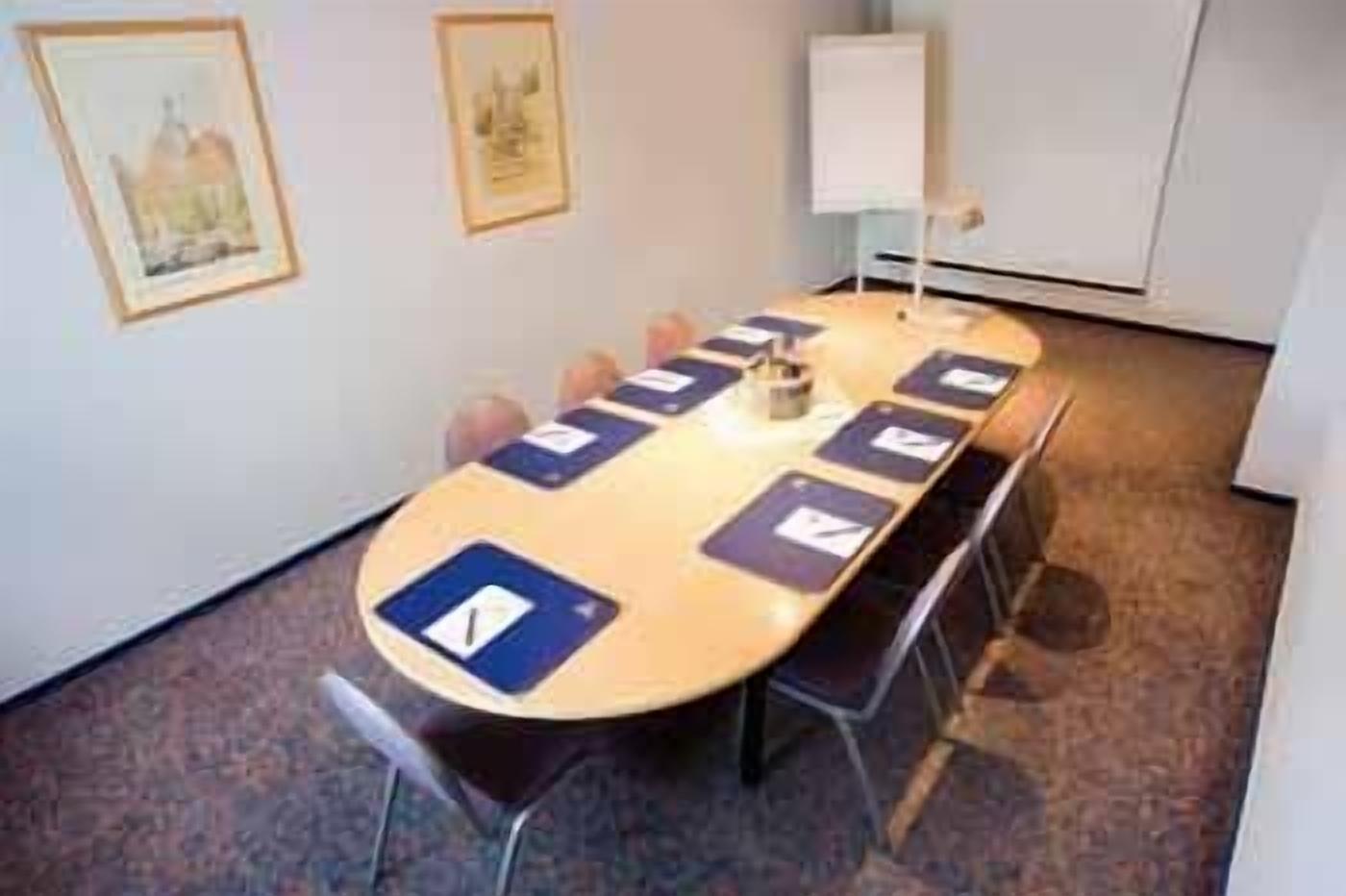 A conference room with a long table, chairs, a whiteboard, and framed pictures on the wall.