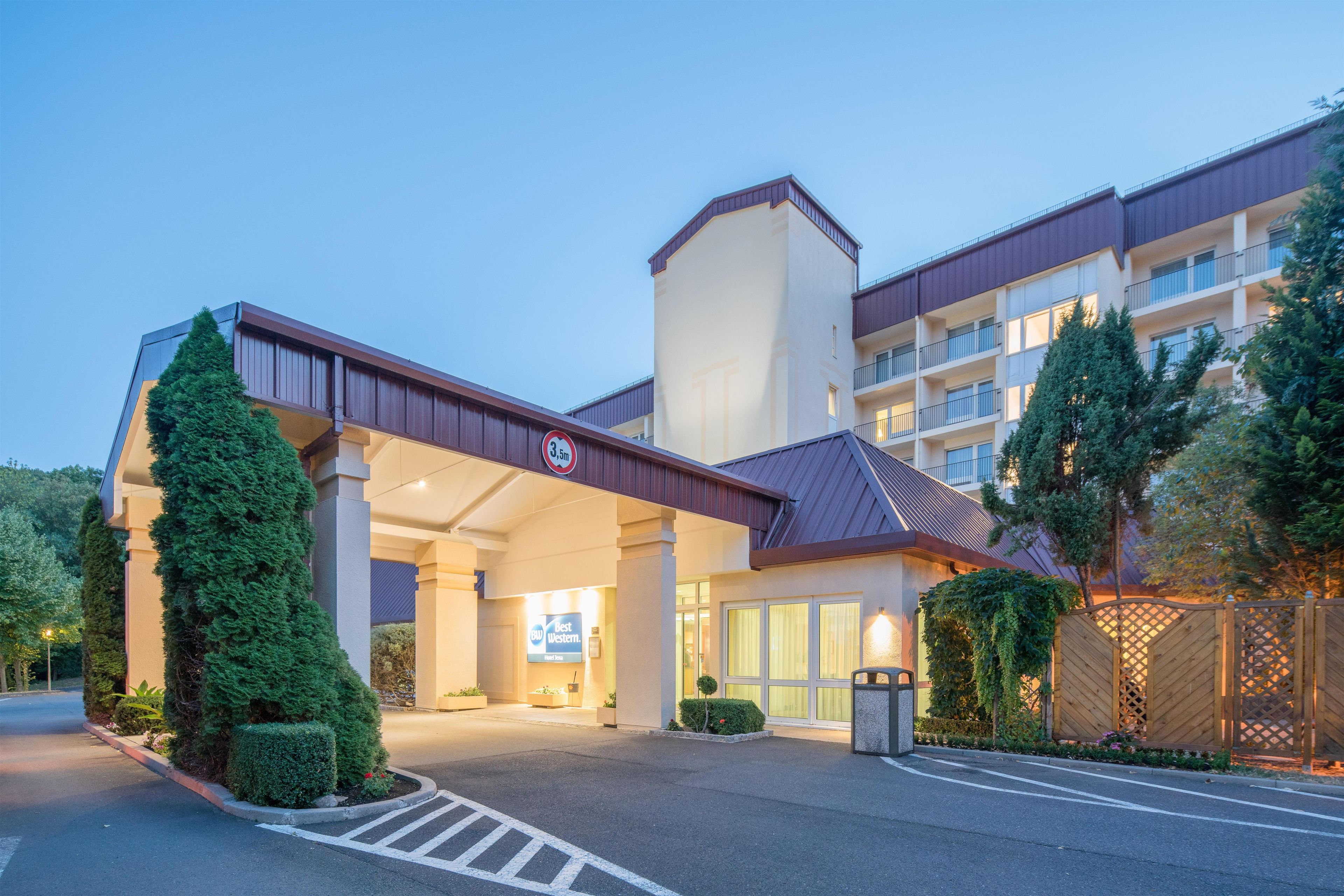 Entrada de un hotel con un paseo techado, un letrero que indica un límite de altura de 3,5 metros y un cartel de Best Western.