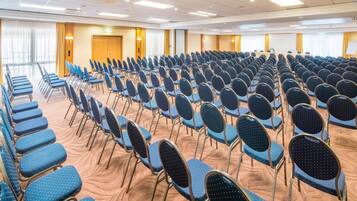 A conference room with rows of chairs, a podium, and a whiteboard.