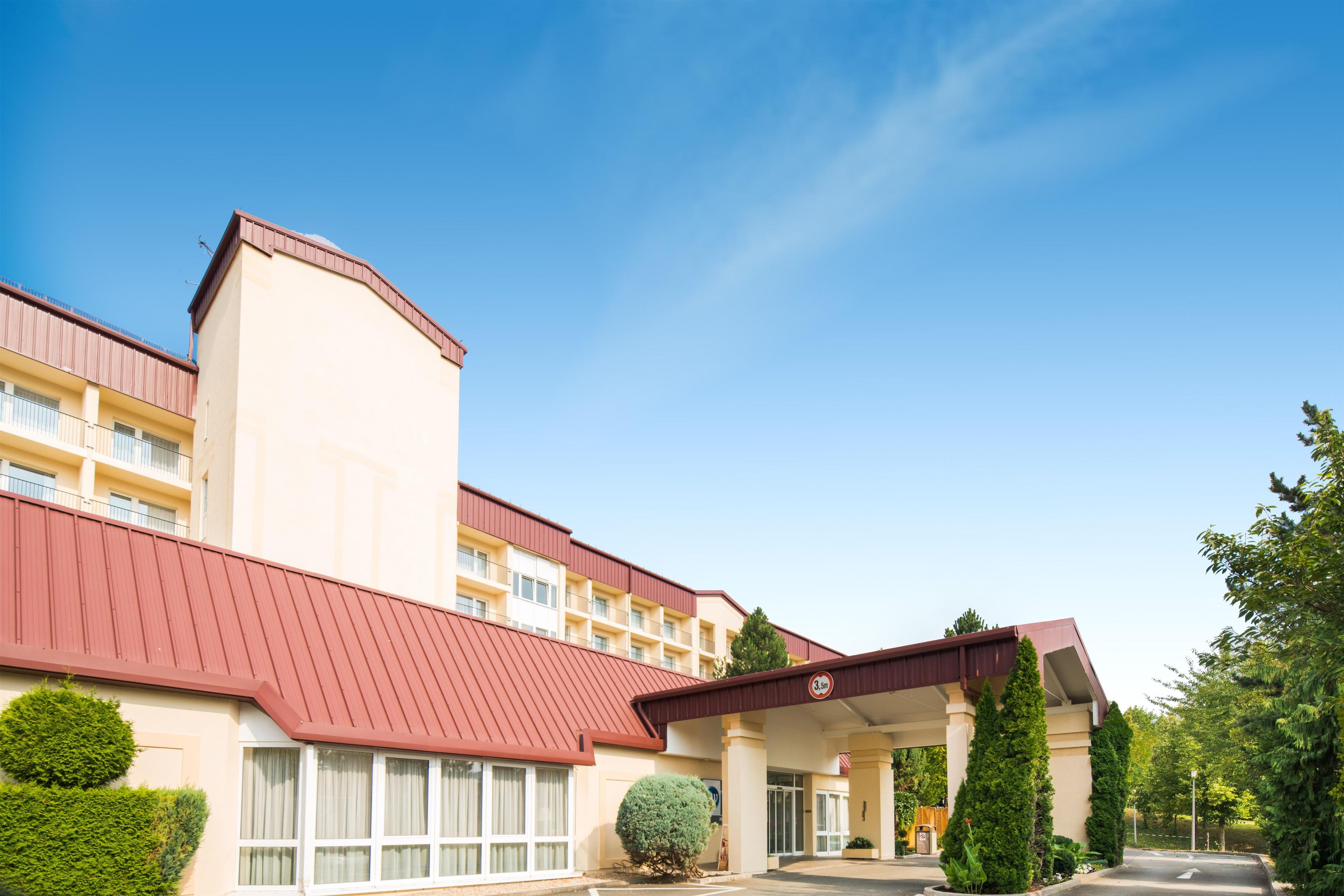 Um hotel com telhado vermelho, vários andares e entrada coberta.