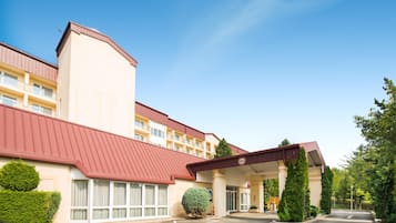 Um hotel com telhado vermelho, vários andares e entrada coberta.