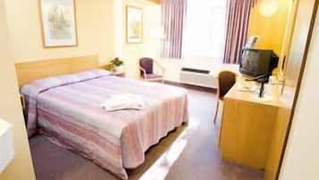Une chambre d’hôtel comprenant un lit, un bureau avec un ordinateur, une chaise et un téléviseur.