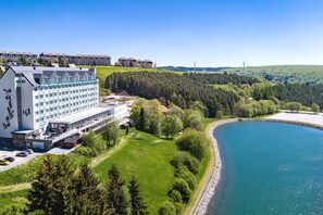 A hotel with a large building, a parking area, and a lake. - Best Western Ahorn Hotel Oberwiesenthal - Adults Only (Oberwiesenthal)