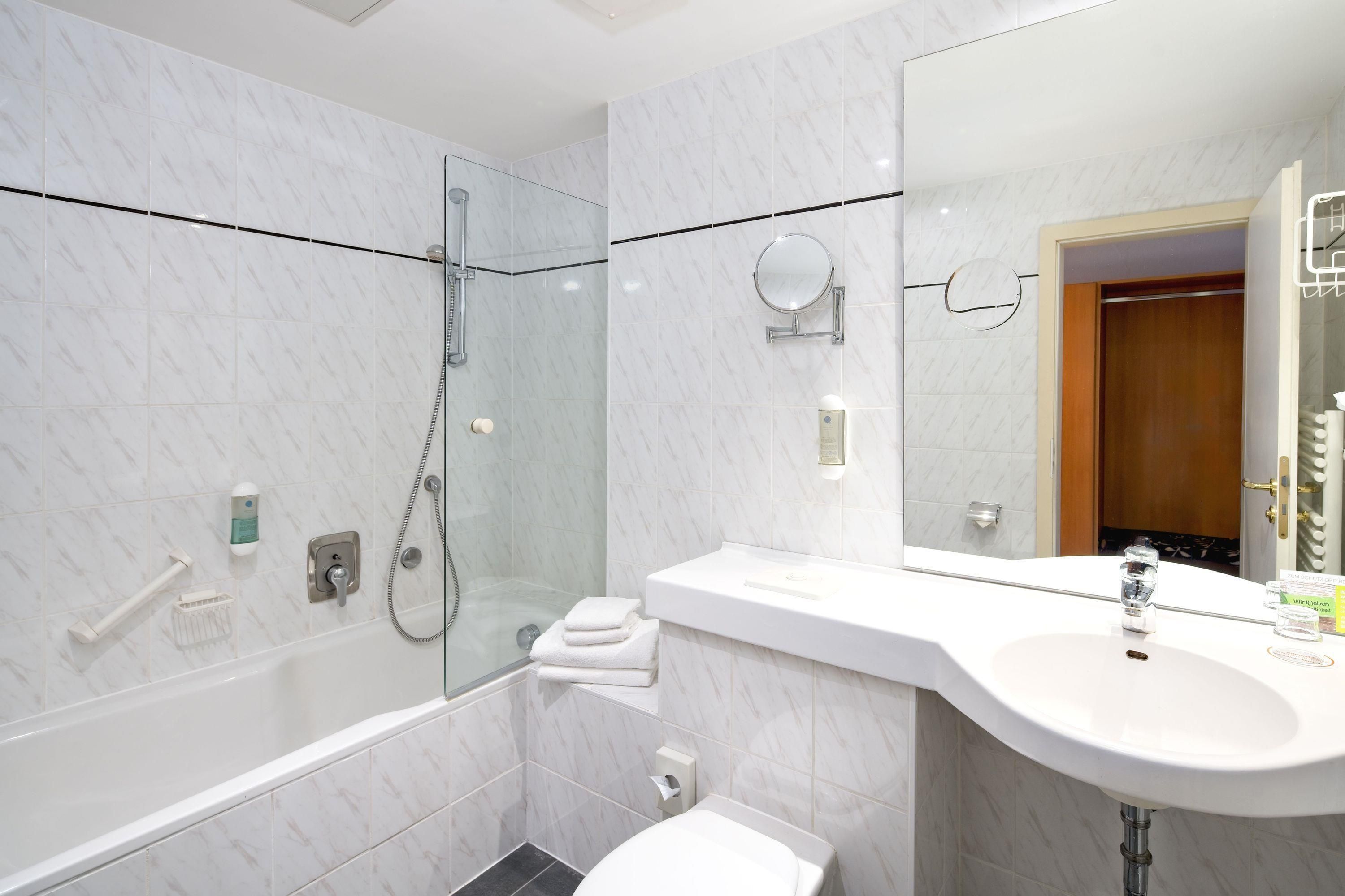 Un baño moderno con ducha envuelta en cristal, tocador con espejo y un inodoro.