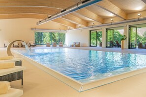 A large indoor swimming pool with clear blue water, surrounded by lounge chairs and a wooden ceiling. - Best Western Ahorn Hotel Oberwiesenthal - Adults Only (Oberwiesenthal)