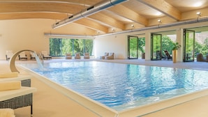 An indoor swimming pool with clear water, wooden ceiling beams, and a view of greenery outside. - Best Western Ahorn Hotel Oberwiesenthal - Adults Only (Oberwiesenthal)