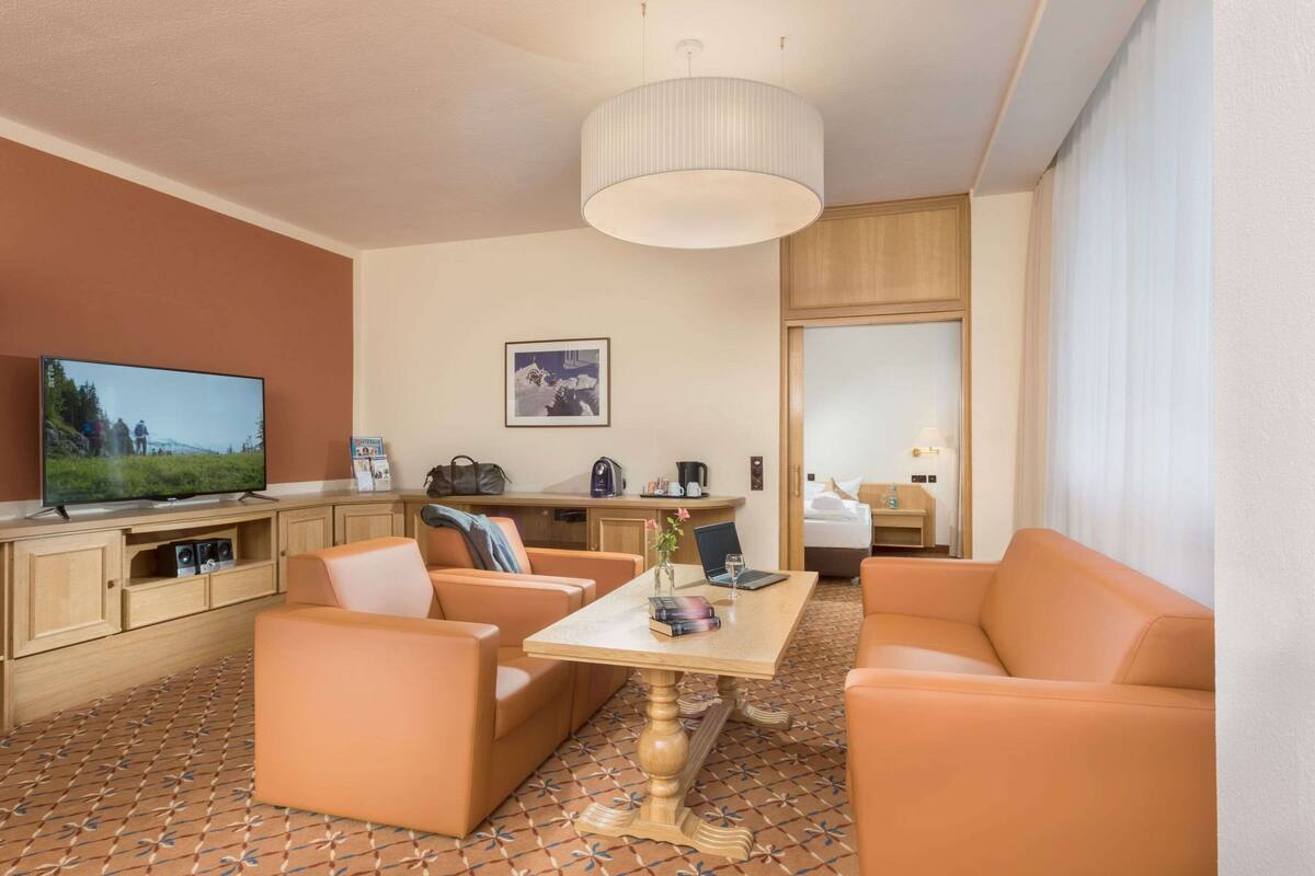 Une chambre d’hôtel équipée d’une télévision, d’un canapé, d’une table et d’un coin cuisine.