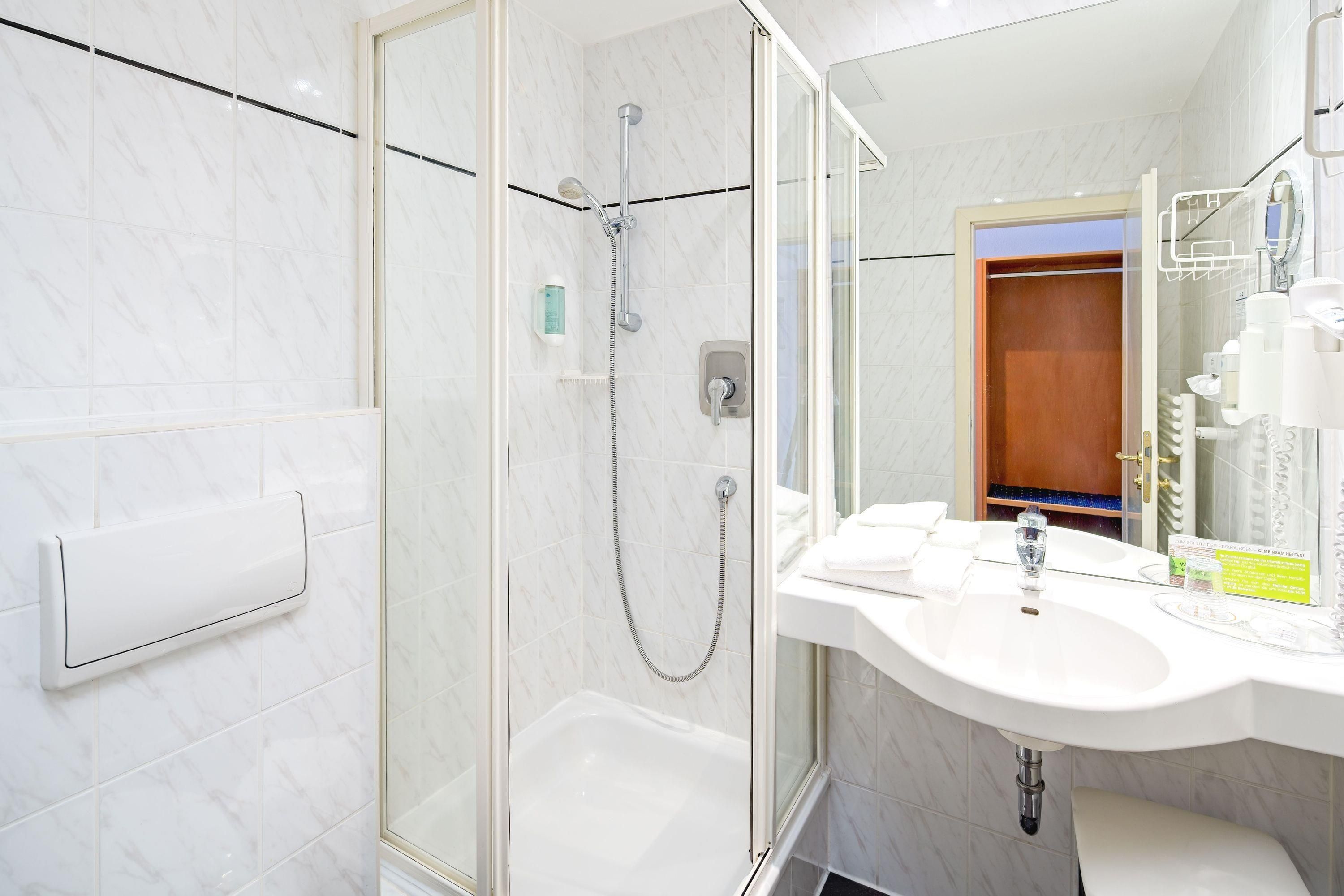 Un bagno moderno con doccia vetrata, lavandino bianco e specchio.