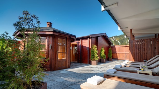 A wooden cabin with a patio area featuring lounge chairs and a small table with towels. - Best Western Ahorn Hotel Oberwiesenthal - Adults Only (Oberwiesenthal)