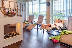 A room with two reclining chairs, a fireplace, and a view of the outdoors. - Best Western Ahorn Hotel Oberwiesenthal - Adults Only (Oberwiesenthal)