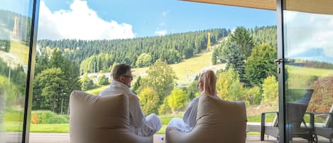 Two people sitting on bean bags facing a scenic view through large glass doors.