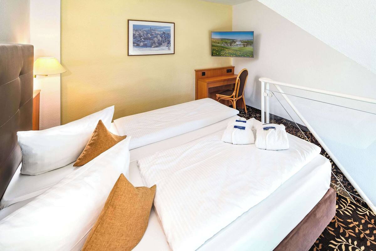 Une chambre d’hôtel avec deux lits, un bureau, une chaise et une vue sur le paysage urbain.