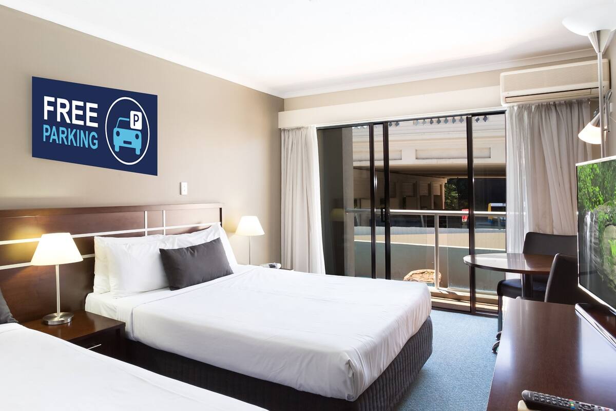 Une chambre d’hôtel équipée d’un lit, d’un bureau, d’une télévision et d’un panneau indiquant que le stationnement est gratuit.