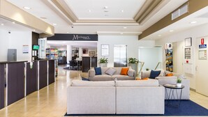 A hotel lobby with a reception desk, a seating area with sofas, and a sign for 'Riverside Hotel Southbank'. - Riverside Hotel Southbank (South Brisbane)