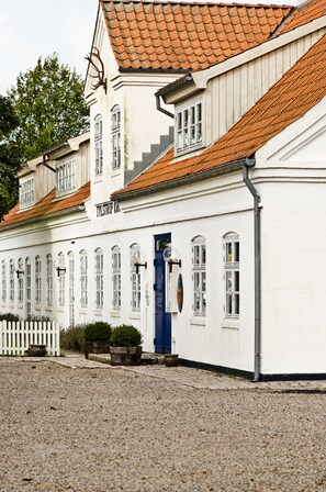 A white building with a red-tiled roof and a blue door, labeled "TYLSTRIP KJ." - Tylstrup Kro og Motel (Tylstrup)