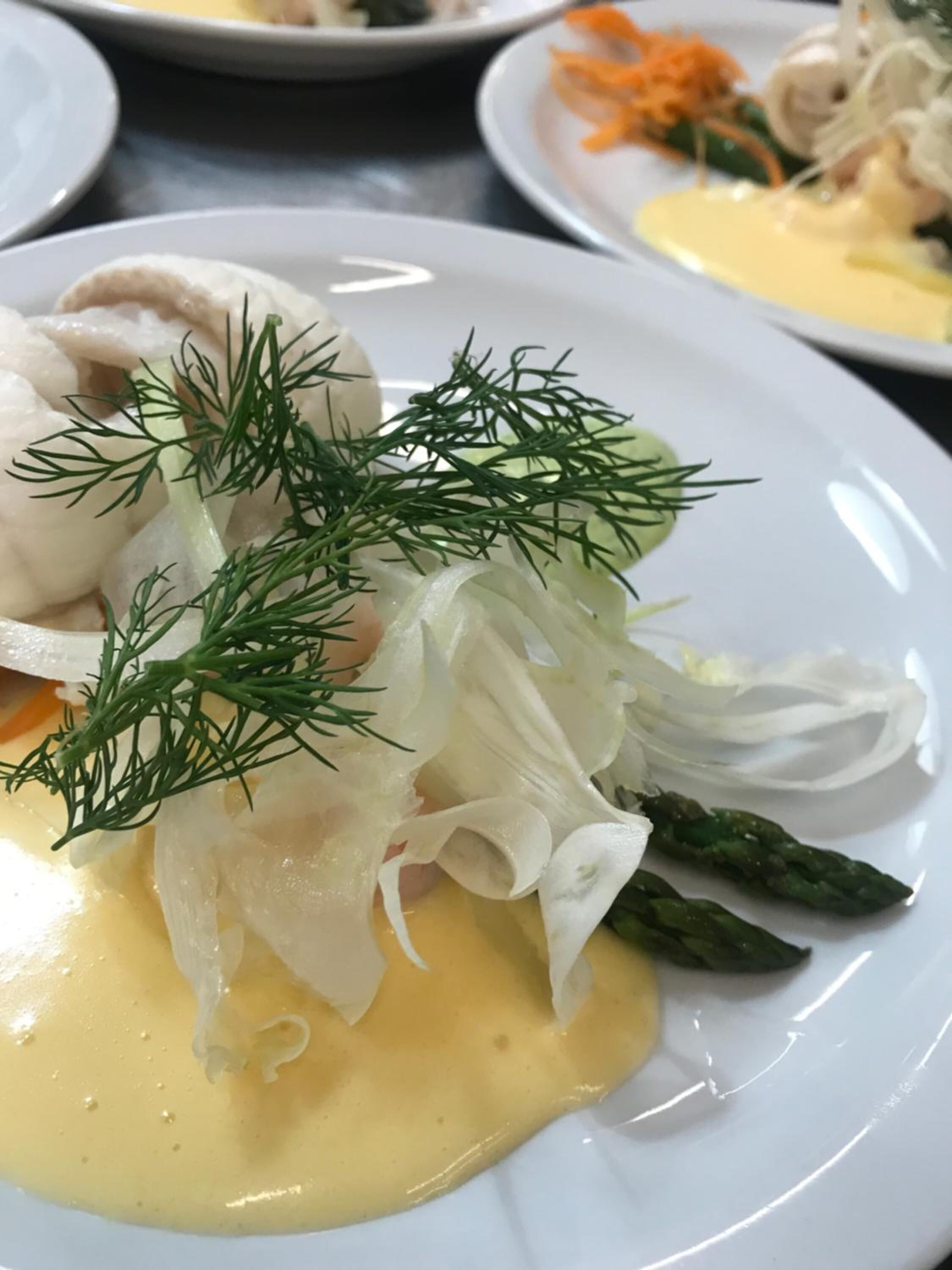 A plate of food with a creamy sauce, asparagus, and a garnish of dill.