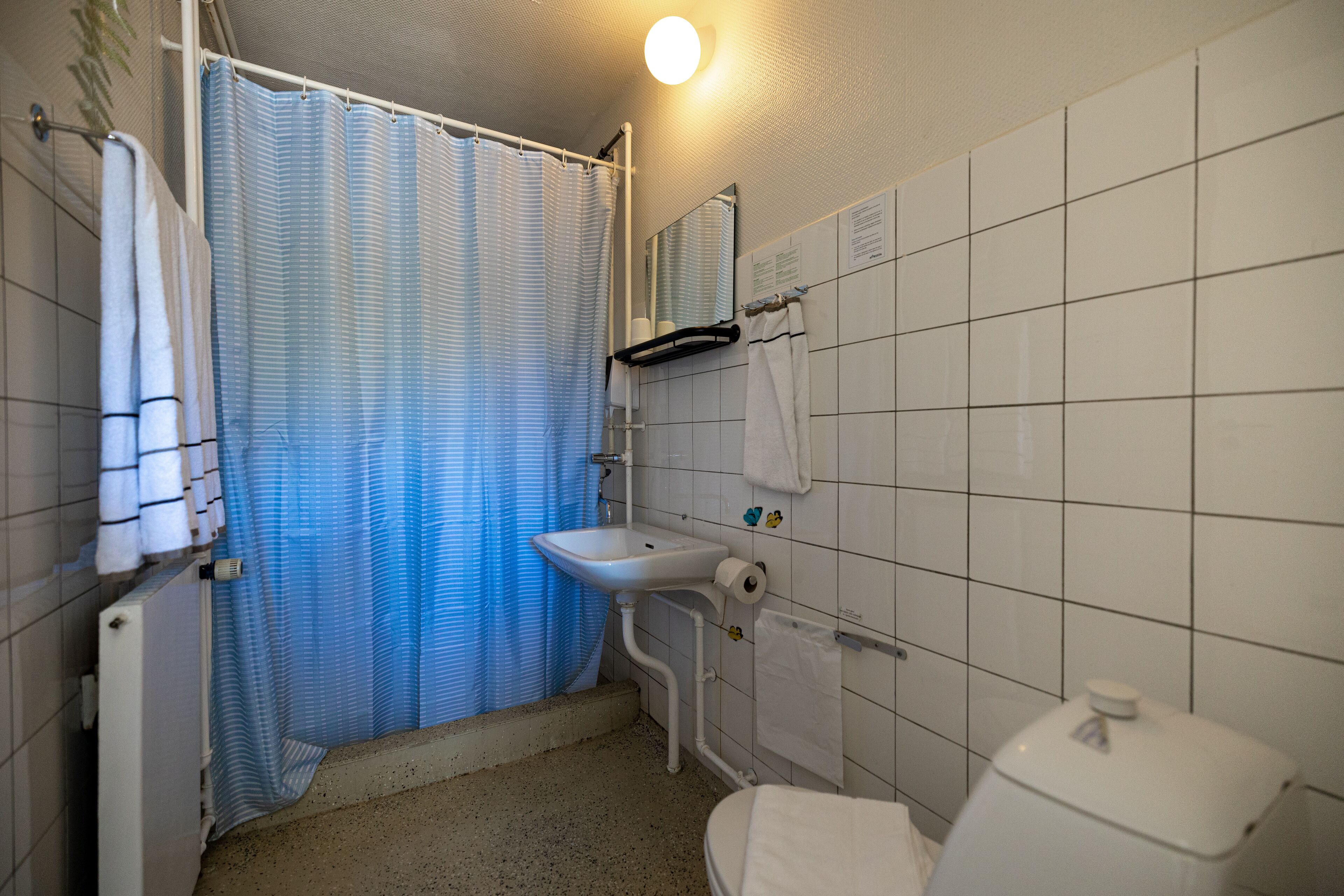 A bathroom with a shower, sink, toilet, and tiled walls.