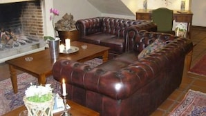 Un salon chaleureux avec un canapé en cuir, une cheminée et une table à manger décorée de bougies.