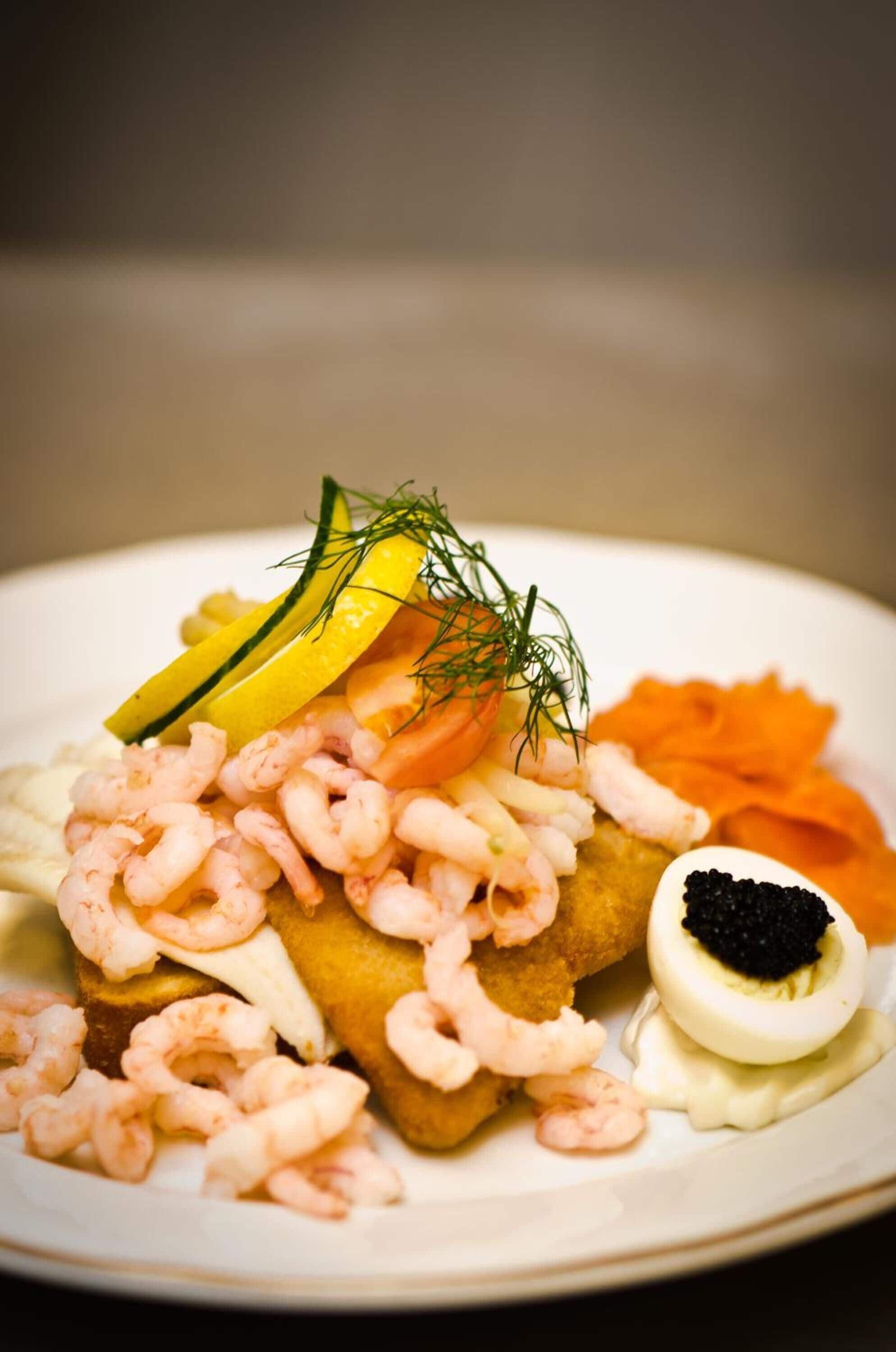 Prato de comida com camarão, rodelas de limão, endro e caviar.