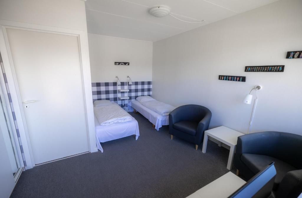 A room with two single beds, a desk, a chair, and a small table.