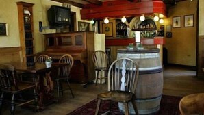 Un espace bar avec des meubles en bois, un grand tonneau et un téléviseur.