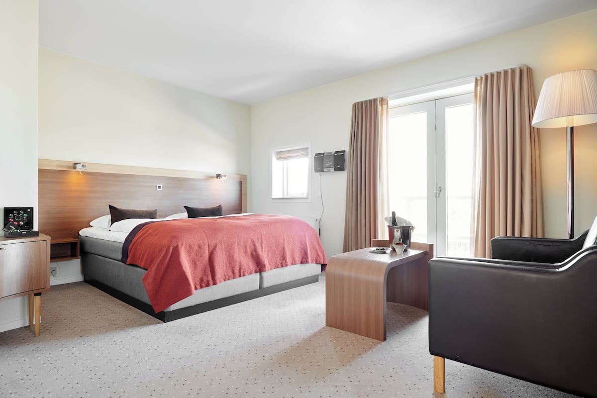 A hotel room with a bed, a desk, a chair, and a TV.