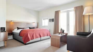 Una habitación de hotel con cama, escritorio, silla y televisor.