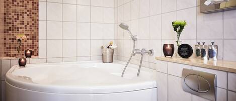 A modern bathroom with a large bathtub, a wall-mounted towel rack, and a shelf with toiletries.