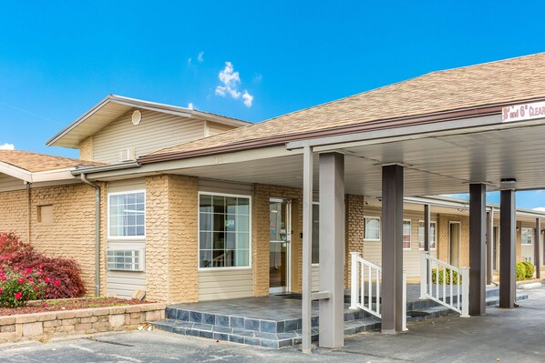 A motel with a covered entrance, a brick facade, and a clear blue sky.