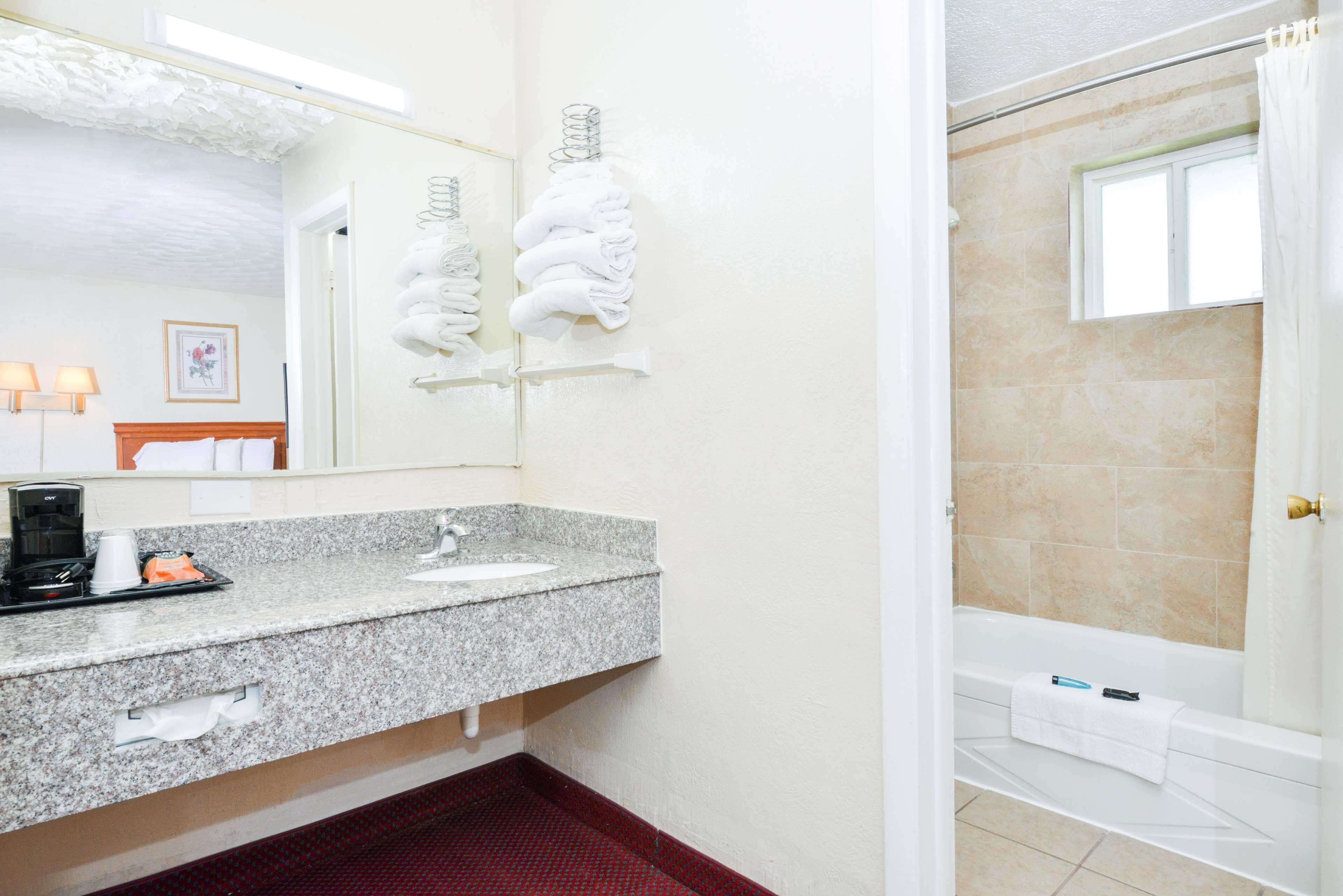 A bathroom with a granite countertop sink, a mirror, and a shower area.