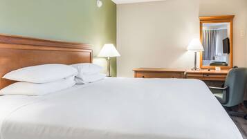 Una habitación de hotel con una cama grande, un escritorio, una silla y un espejo.
