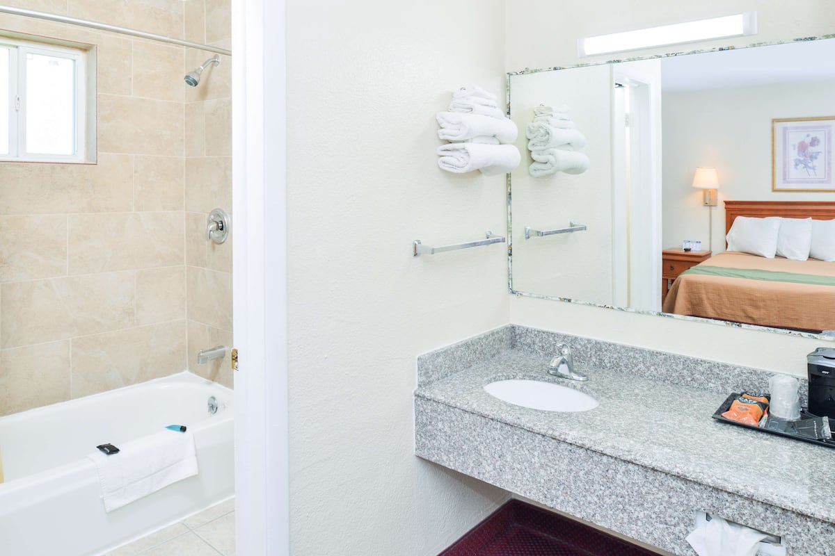 A bathroom with a bathtub, a sink, and a mirror.
